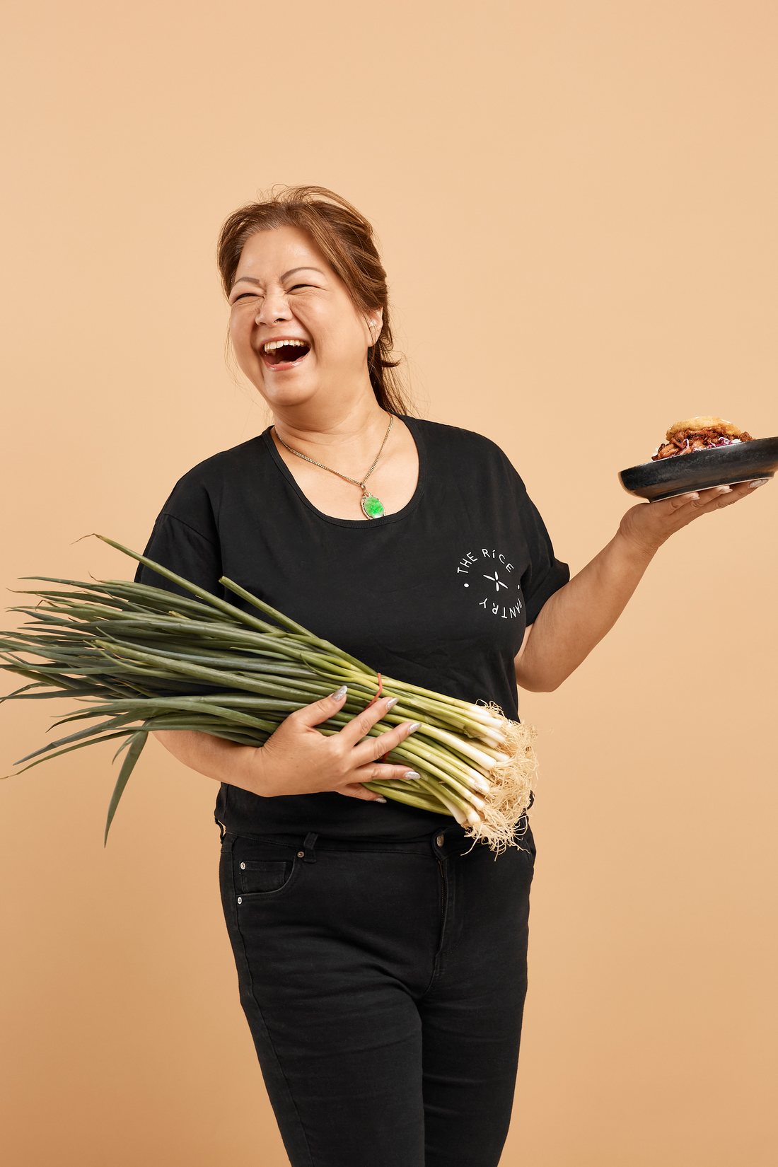 Mama Le, Rice Pantry's Catering Head Chef, holding fresh spring onions